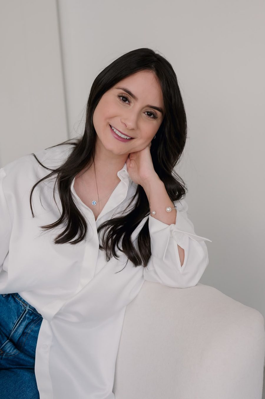 Retrato de Bruna Almeida sorrindo, com a mão apoiada no rosto